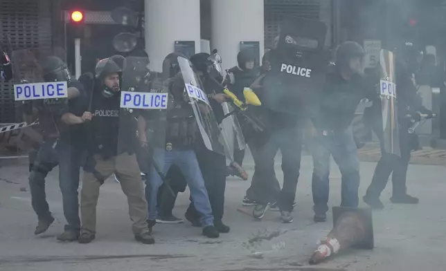 Law enforcement officers gather as tear gas fills the air during a protest after federal immigration authorities conducted an operation on Friday, June 6, 2025, in Los Angeles. (AP Photo/Jae C. Hong)