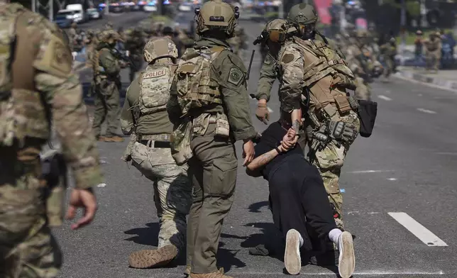 Police detain a man during a protest in the Paramount section of Los Angeles, Saturday, June 7, 2025, after federal immigration authorities conducted operations. (AP Photo/Eric Thayer)