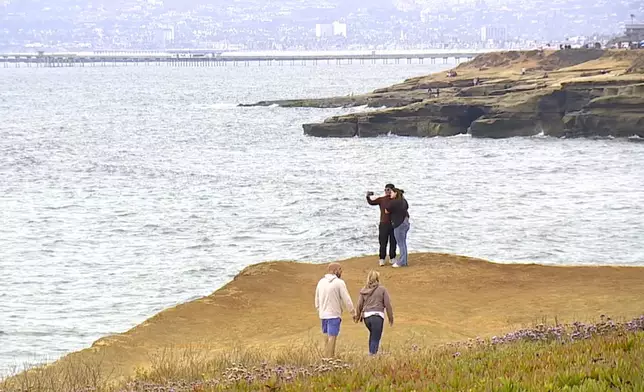 This image taken from video provided by KGTV shows people on a cliff near where a twin-engine Cessna 414 crashed on Sunday, June 8, 2025, leaving a debris field about 3 miles west of Point Loma, a San Diego neighborhood that juts into the Pacific. (KGTV via AP)
