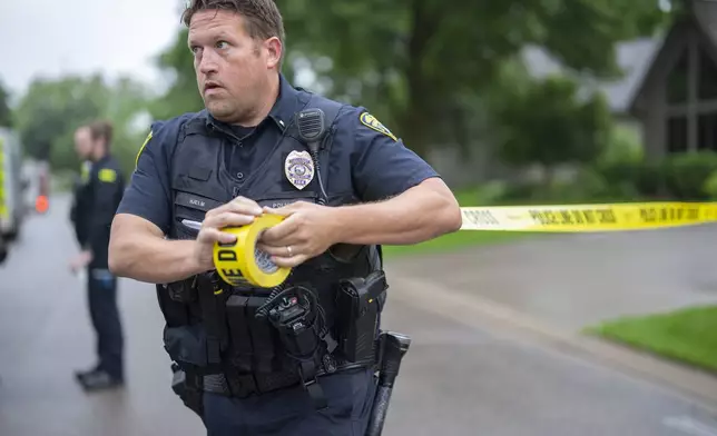 Brooklyn Park Police Lieutenant Hjelm sets up a perimeter with police tape near the scene of a shooting in Brooklyn Park, Minn. on Saturday, June 14, 2025. (Alex Kormann/Star Tribune via AP)