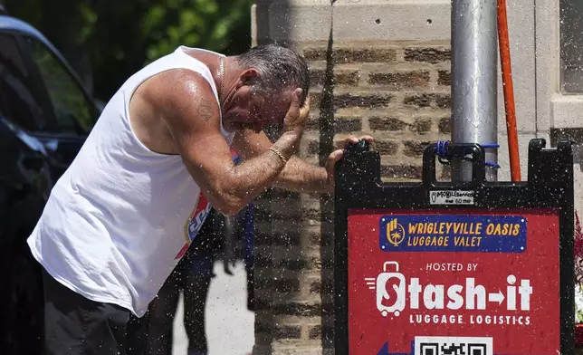 A man cools off under a sprinkler provided by a Chicago Fire Department during hot weather in Chicago, Sunday, June 22, 2025. (AP Photo/Nam Y. Huh)