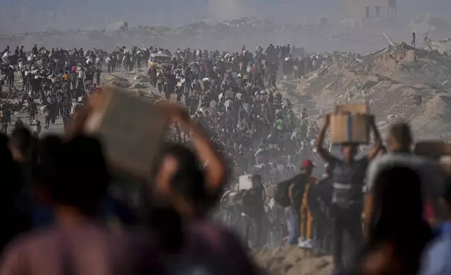 Palestinians carry sacks and boxes of food and humanitarian aid unloaded from a World Food Program convoy that had been heading to Gaza City, in the northern Gaza Strip, Monday, June 16, 2025. (AP Photo/Jehad Alshrafi)