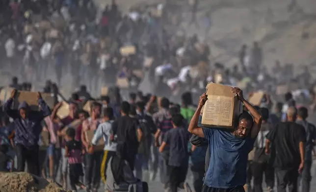 Palestinians carry sacks and boxes of food and humanitarian aid unloaded from a World Food Program convoy that had been heading to Gaza City, in the northern Gaza Strip, Monday, June 16, 2025. (AP Photo/Jehad Alshrafi)