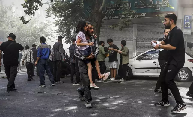 A man carries a wounded girl after an explosion in downtown Tehran amid Israel's three-day campaign of strikes against Iran, Sunday, June 15, 2025. (AP Photo/Morteza Zangene/ISNA)