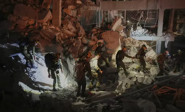 Israeli security forces inspect a destroyed building that was hit by a missile fired from Iran, near Tel Aviv, Israel, early Sunday, June 15, 2025. (AP Photo/Ohad Zwigenberg)