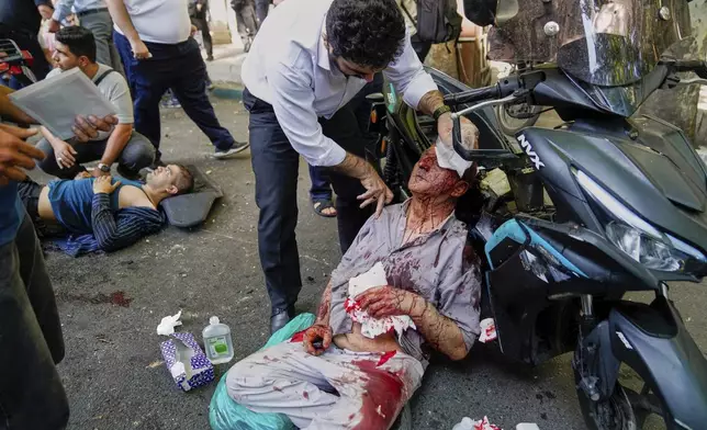 An injured man is assisted in the street after an explosion in downtown Tehran, amid Israel's three-day campaign of strikes against Iran, Sunday, June 15, 2025. (AP Photo/Amir Kholousi/ISNA)