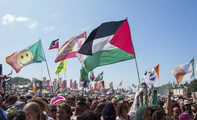 The flag of Palestine is waved in a crowd of festivalgoers at the hip hop trio Kneecap's performance during the Glastonbury Festival in Worthy Farm, Somerset, England, Saturday, June 28, 2025. (Scott A Garfitt/Invision/AP)