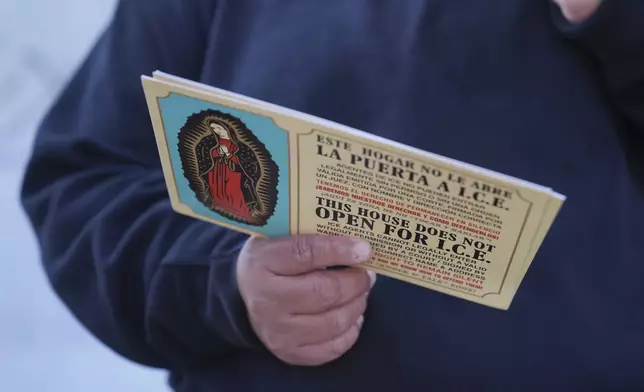 FILE - A woman outside Ambiance Apparel holds a card about Immigration and Customs Enforcement after authorities conducted an operation, Friday, June 6, 2025, in Los Angeles. (AP Photo/Jae C. Hong, File)
