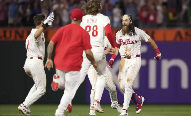 Philadelphia Phillies' Brandon Marsh, right, celebrates with teammates after hitting a game-winning RBI-single against Chicago Cubs pitcher Daniel Palencia during the 11th inning of a baseball game Monday, June 9, 2025, in Philadelphia. (AP Photo/Matt Slocum)