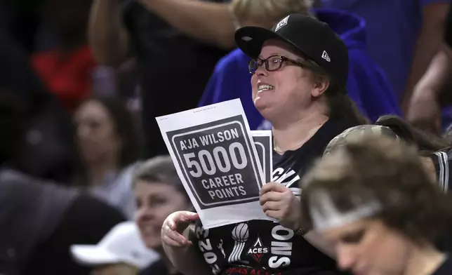 A fan holds a up a sign after Las Vegas Aces center A'ja Wilson (22) scores a basket to achieve her 5,000th career point in the WNBA during the first half of a WNBA basketball game against the Connecticut Sun, Wednesday, June 25, 2025, in Las Vegas. (Steve Marcus/Las Vegas Sun via AP)