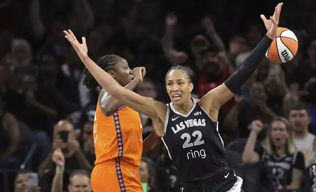 Las Vegas Aces center A'ja Wilson (22) celebrates after scoring a basket against Connecticut Sun center Tina Charles, left, to achieve her 5,000th career point in the WNBA during the first half of a WNBA basketball game Wednesday, June 25, 2025, in Las Vegas. (Steve Marcus/Las Vegas Sun via AP)