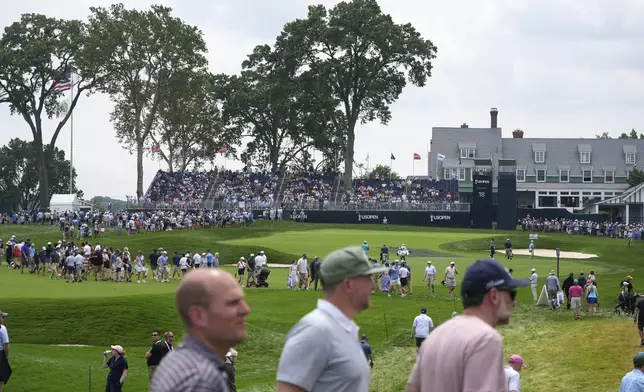 Fans cross the 18th fairway, in front of the green and clubhouse, between groups of golfers during a practice round for the 2025 US Open golf championship at Oakmont Country Club in Oakmont, Pa., Monday, June 9, 2025. (AP Photo/Gene J. Puskar)