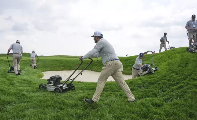 The rough surrounding a fairway bunker on the 18th hole gets trimmed during a practice round for the 2025 US Open golf championship at Oakmont Country Club in Oakmont, Pa., Monday, June 9, 2025. (AP Photo/Gene J. Puskar)