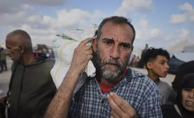 Palestinians carry bags filled with food and humanitarian aid provided by the Gaza Humanitarian Foundation, a U.S.-backed organization approved by Israel, in Khan Younis, southern Gaza Strip, on Tuesday, June 3, 2025. (AP Photo/Abdel Kareem Hana)