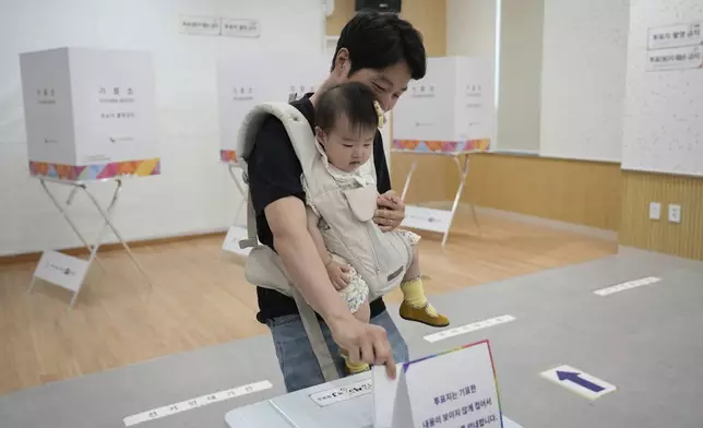 A man casts his vote with a baby for presidential election at a polling station in Seoul, South Korea, Tuesday, June 3, 2025.(AP Photo/Ahn Young-joon)