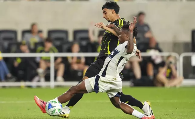Vancouver Whitecaps defender Édier Ocampo, right, tackles Columbus Crew midfielder Taha Habroune, left, during the second half of an MLS soccer match Saturday, June 14, 2025, in Columbus, Ohio. (AP Photo/Jeff Dean)