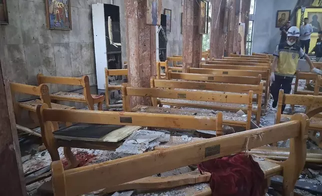 In this photo released by the Syrian official news agency SANA, a Civil Defence worker inspects the damage inside Mar Elias church where a suicide bomber detonated himself in Dweil'a in the outskirts of Damascus, Syria, Sunday June 22, 2025. (SANA via AP)