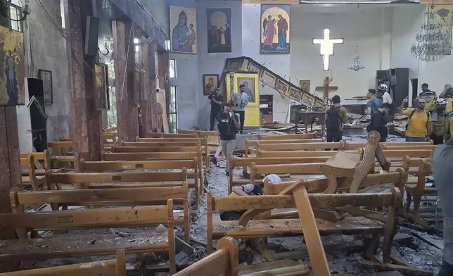 In this photo released by the Syrian official news agency SANA, journalists and Civil Defence workers inspect the damage inside Mar Elias church where a suicide bomber detonated himself in Dweil'a in the outskirts of Damascus, Syria, Sunday June 22, 2025. (SANA via AP)