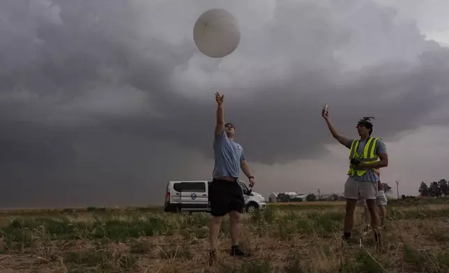 Red team and Project ICECHIP members Wyatt Ficek, left, and Ethan Mok, right, release a latex weather balloon with an attached instrument called a windsond into the inflow region of a storm to collect data during a Project ICECHIP operation Thursday, June 5, 2025, near Morton, Texas. (AP Photo/Carolyn Kaster)