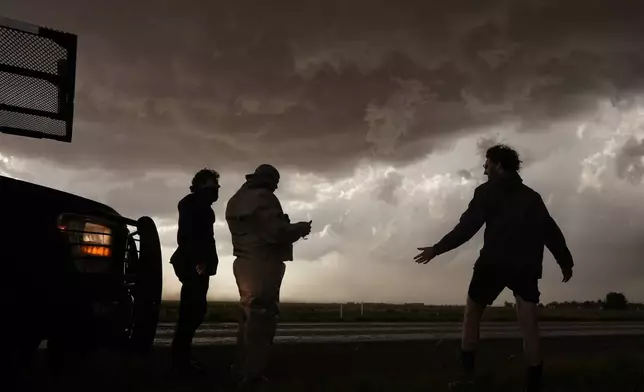 Joey Toniolo, from left, Tim Marshall and Tony Illenden stand next to Northern Illinois University's Husky Hail Hunter as storm clouds gather during a Project ICECHIP operation Friday, June 6, 2025, in Meadow, Texas. (AP Photo/Carolyn Kaster)