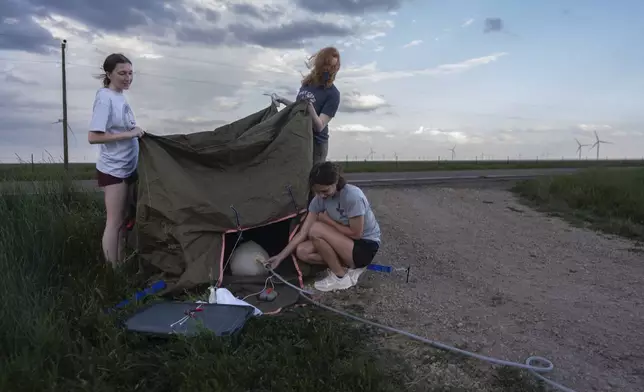 Project ICECHIP members from Northern Illinois University on the black team including Evelynn Mantia, left, and Olivena Carlisle, lower right, inflate a weather balloon with a radiosonde attached to collect data Wednesday, June 4, 2025, in Tucumcari, N.M. (AP Photo/Carolyn Kaster)