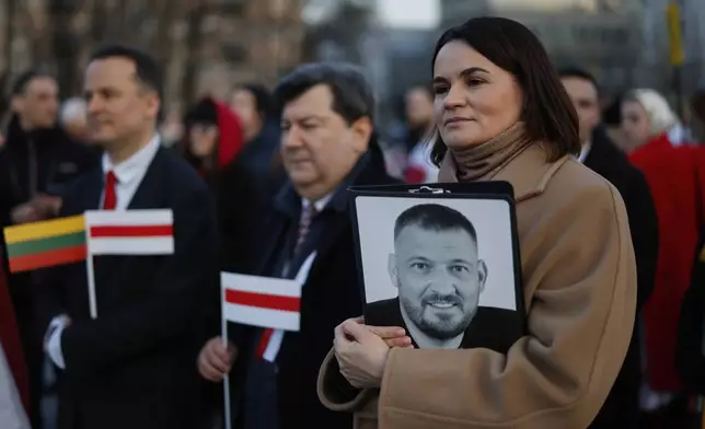 FILE - Belarusian opposition leader Sviatlana Tsikhanouskaya, right, holds a photo of her imprisoned husband, Syarhei Tsikhanouski as she attends a celebration marking the 107th anniversary of the declaration of independence of the Belarusian People's Republic, in Vilnius, Lithuania, on March 25, 2025. (AP Photo/Mindaugas Kulbis, File)