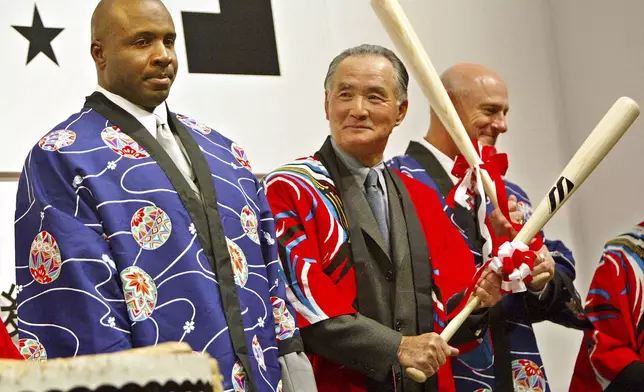 FILE - Wearing traditional Japanese "Hapi" coats San Francisco Giants star Barry Bonds, left, is watched by Japanese baseball legend Shigeo Nagashima standing near New York Mets manager Art Howe after breaking open a barrel of sake with baseball bats at a party in Tokyo in this Nov. 7, 2002.(AP Photo/David Guttenfelder, File)