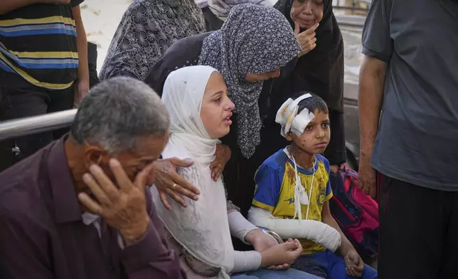Hamam Al-Farani sits next to his sister, in white, along with other family members as the body of their father Alaa, killed in an Israeli army strike that also injured the boy, is prepared for burial at Shifa hospital in Gaza City, on Tuesday, June 24, 2025. (AP Photo/Jehad Alshrafi)