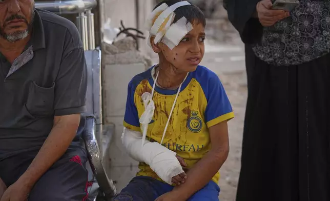 Hamam Al-Farani, sits along with other family members as the body of his father, Alaa, killed in an Israeli army strike that also injured the boy, is prepared for burial at Shifa hospital in Gaza City, Tuesday, June 24, 2025. (AP Photo/Jehad Alshrafi)