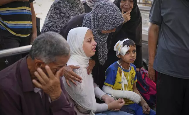 Hamam Al-Farani sits next to his sister, in white, along with other family members as the body of their father Alaa, killed in an Israeli army strike that also injured the boy, is prepared for burial at Shifa hospital in Gaza City, on Tuesday, June 24, 2025. (AP Photo/Jehad Alshrafi)
