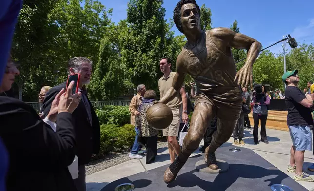 People gather around the statue of former NBA basketball player and coach Lenny Wilkens after its unveiling outside of Climate Pledge Arena, Saturday, June 28, 2025, in Seattle. (AP Photo/Lindsey Wasson)