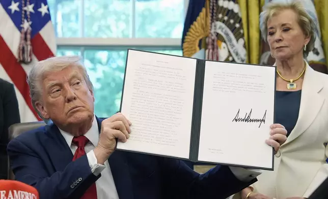 FILE - President Donald Trump holds a signed an executive order relating to school discipline policies as Education Secretary Linda McMahon listens in the Oval Office of the White House, April 23, 2025, in Washington. (AP Photo/Alex Brandon, file)