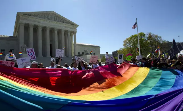 FILE - Demonstrators hold a rainbow pride flag outside the Supreme Court as justices deliberate Obergefell vs. Hodges, the case that legalized same-sex marriage nationwide, in Washington, April 28, 2015. (AP Photo/Jose Luis Magana, File)
