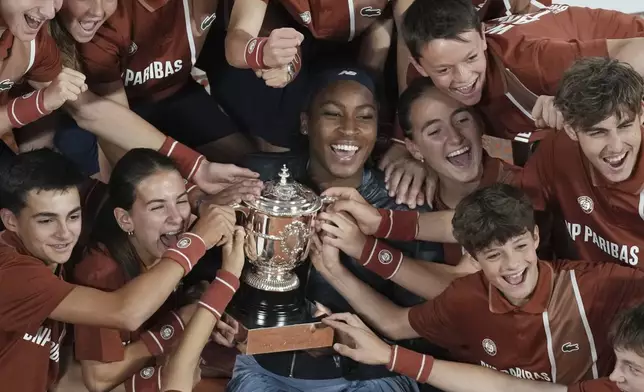 Winner Coco Gauff of the U.S. and ball boys and girls pose with the trophy after the final match of the French Tennis Open against Aryna Sabalenka of Belarus at the Roland-Garros stadium in Paris, Saturday, June 7, 2025. (AP Photo/Christophe Ena)