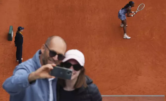 A couple makes a selfie during the final match of the French Tennis Open between Aryna Sabalenka of Belarus and United States' Coco Gauff at the Roland-Garros in Paris, Saturday, June 7, 2025. (AP Photo/Lindsey Wasson)