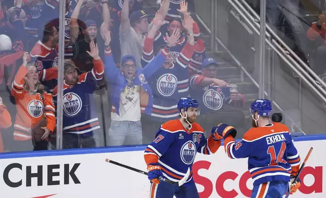 Edmonton Oilers' Connor McDavid (97) and Mattias Ekholm (14) celebrate Ekholm's tying goal against the Florida Panthers during the third period in Game 1 of the NHL hockey Stanley Cup final series in Edmonton, Alberta, Wednesday, June 4, 2025. (Darryl Dyck/The Canadian Press via AP)
