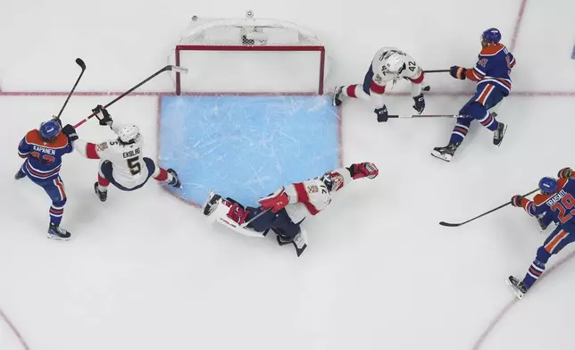 Edmonton Oilers' Leon Draisaitl (29) scores against Florida Panthers goalie Sergei Bobrovsky (72) as Aaron Ekblad (5) and Gustav Forsling (42) defend while Edmonton's Kasperi Kapanen (42) and Evander Kane (91) watch during the first overtime period in Game 1 of the NHL Stanley Cup Final, in Edmonton, Alberta, on Wednesday, June 4, 2025. (Darryl Dyck//The Canadian Press via AP)