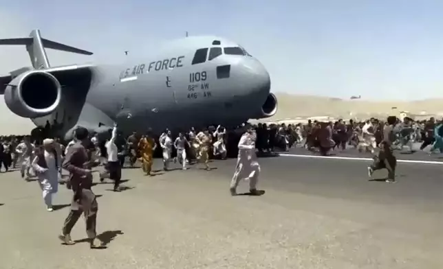 FILE - Hundreds of people desperate to escape Afghanistan run alongside a U.S. Air Force plane as it moves down a runway of the international airport in Kabul, Monday, Aug.16. 2021. (AP Photo, File)