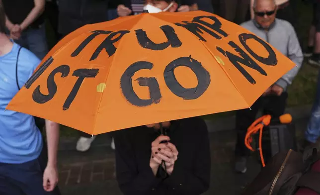 A demonstrators carries an umbrella with protest language on it during before a march taking place on the day of a military parade commemorating the Army's 250th anniversary, coinciding with President Donald Trump's 79th birthday, Saturday, June 14, 2025, in Washington. (AP Photo/Evan Vucci)