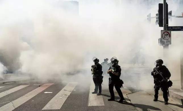 Law enforcement officers stand guard after deploying tear gas during a protest Saturday, June 14, 2025, in Los Angeles. (AP Photo/Noah Berger)