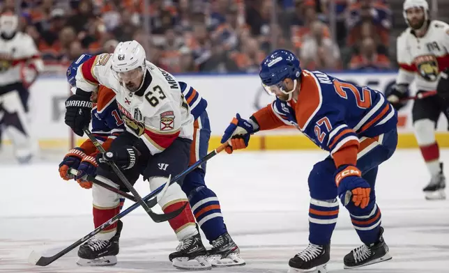 Florida Panthers' Brad Marchand (63) and Edmonton Oilers' Brett Kulak (27) battle for the puck during the third period in Game 1 of the NHL hockey Stanley Cup final series in Edmonton, Alberta, Wednesday, June 4, 2025. (Jason Franson/The Canadian Press via AP)