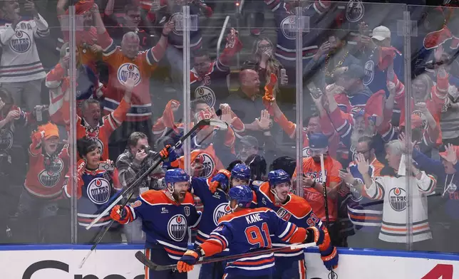 Edmonton Oilers' Leon Draisaitl, from left to right, Evan Bouchard, Evander Kane, Ryan Nugent-Hopkins celebrate Draisaitl's winning goal during the first overtime period in Game 1 of the NHL Stanley Cup Final against the Florida Panthers, in Edmonton, Alberta, on Wednesday, June 4, 2025. (Darryl Dyck//The Canadian Press via AP)