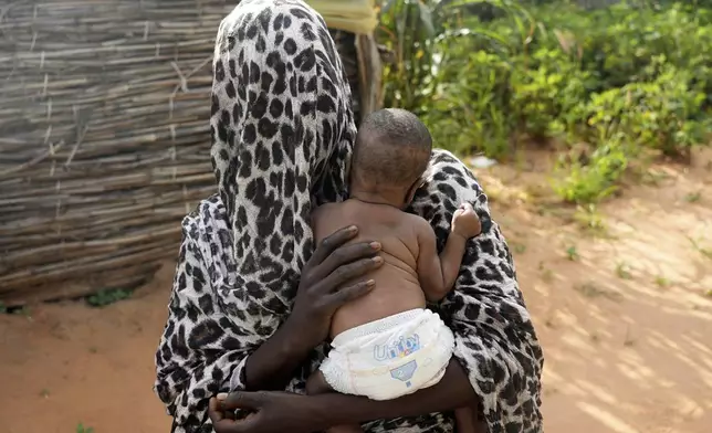 FILE - A woman who fled war in Sudan and requested anonymity because she feared retribution after reporting sexual exploitation, holds her baby in a refugee camp in Adre, Chad, Oct. 5, 2024. (AP Photo/Sam Mednick, File)