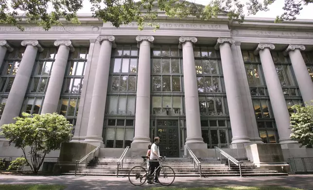 FILE - A bicyclist walks by Langdell Hall, the Harvard Law Library, on the Harvard Law School campus at Harvard University, Aug. 1, 2005, in Cambridge, Mass. (AP Photo/Charles Krupa, File)