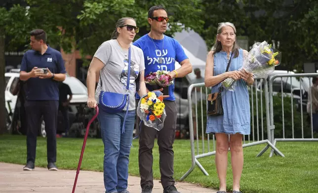 From left, Carrie Spyva-McIlvaine, Gabriel Velasco and Lisa Turnquist arrive to place bouquets of flowers at a growing memorial outside of the Boulder County, Colo., courthouse after Sunday's attack Monday, June 2, 2025, in Boulder, Colo. (AP Photo/David Zalubowski)