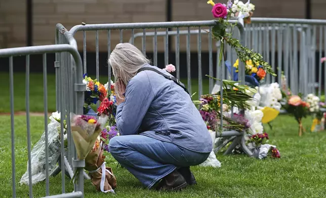 A visitor offers a tribute after leaving a bouquet of flowers at a makeshift memorial for victims of an attack outside of the Boulder County, Colo., courthouse as a light rain falls Tuesday, June 3, 2025, in Boulder, Colo. (AP Photo/David Zalubowski)