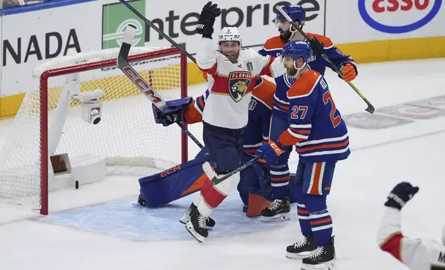 Florida Panthers' Sam Bennett (9) celebrates Brad Marchand's goal against Edmonton Oilers goalie Stuart Skinner as Brett Kulak (27) and Jake Walman (96) look on during the first period in Game 1 of the NHL hockey Stanley Cup final series in Edmonton, Alberta, Wednesday, June 4, 2025. (Darryl Dyck/The Canadian Press via AP)