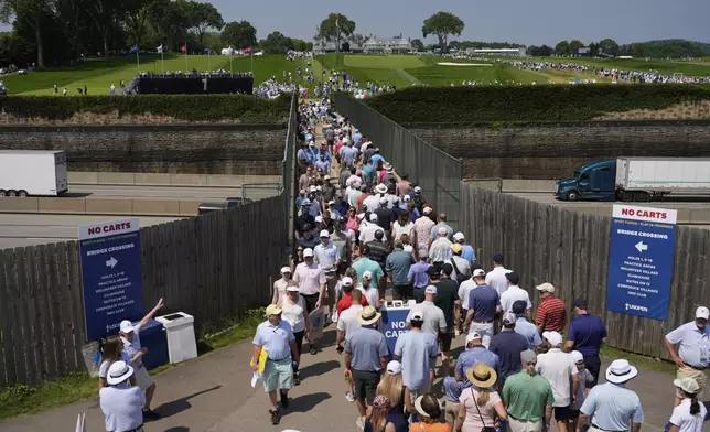 Fans use a pedestrian bridge over the Pennsylvania Turnpike, which divides Oakmont Country Club, during a practice round ahead of the U.S. Open golf tournament Wednesday, June 11, 2025, in Oakmont, Pa. (AP Photo/Carolyn Kaster)