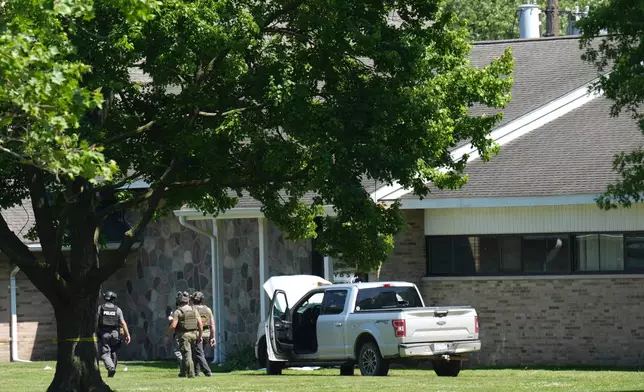 Police walk by an idle vehicle near CrossPointe Community Church in Wayne, Mich., Sunday, June 23, 2025. (AP Photo/Paul Sancya)