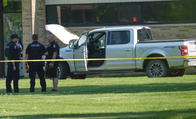 Police walk by an idle vehicle near CrossPointe Community Church in Wayne, Mich., Sunday, June 23, 2025. (AP Photo/Paul Sancya)